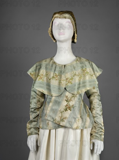 Women's caraco 18th century, blue and white silk brocaded and embellished with rose branches. Straight-cut front fastened with hooks, slightly overlapping lapels; low neckline finished with a large turn-down semicircular collar; long set-in narrow sleeves. Back cut with triangular gussets widened at the bottom and waist to create a generous basque/ruffle. Dark blue canvas lining; lace-up waistband at the lining. Inside, under the flaps at the sides, a wide red canvas belt is sewn on and laced at the front. Second variant: cream silk with blue stripes and colorful floral branches, fitted at the top; overlapping lapels with sides sewn on the bias; large turn-down semicircular collar covering the shoulders and falling deeply into the back; long set-in narrow sleeves cut in a curve at elbow height; back fitted at the waist and widened below by triangular gussets. Europe, 1770s. Garment; length 56.5 cm, bottom circumference 249 cm. Maker: unknown. Creator name: Józef Brandt 1841–1915 noted....