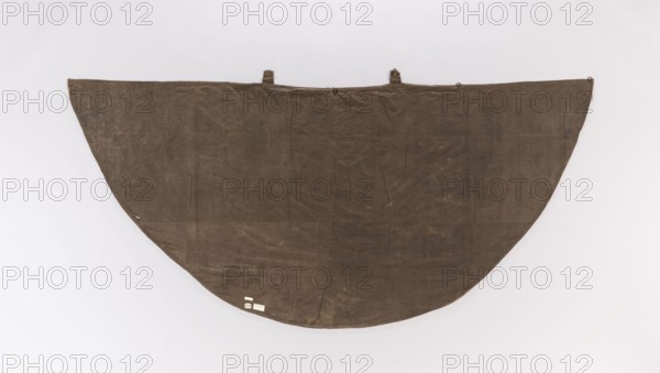 Church cope, flowers, leaves, liturgical vestments, plant ornaments, sacred art; church paraments; made of silk fabric brocaded with colorful threads green, cream, blue-pink, cherry; 18th century, France; liturgical vestments; height 137 cm, width 302.5 cm., A large semicircular fabric panel hangs against a plain light background, appearing worn with visible creases and seams; the fabric is predominantly brown with areas of darker and lighter brown shading, and there are a few small attachments along the top edge and a few small pale tags near the lower curve.