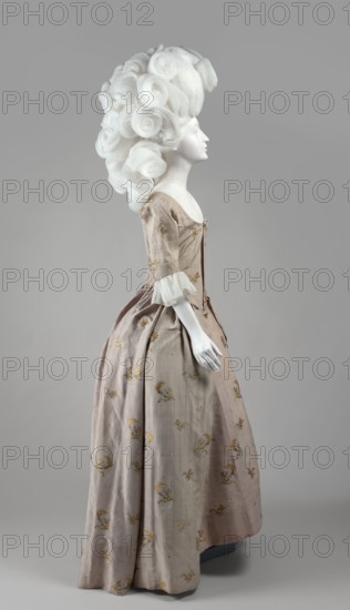 Robe à l'anglaise dress, purchase provenance noted, flower bouquets ornament, gathers clothing decoration, patterned fabrics, clothing, silk fabrics, floral patterns, women's clothing, women's fashion, 18th century clothing, English-style outer dress, made of pale pink silk with patterns of tiny flower bouquets, with a close-fitting lace at the back, fitted with cuts and stiffened with boning. Laced at the front, without a separate bodice, with a wrap-around bodice. Large, round neckline. Narrow, elbow-length set-in sleeves. Outer skirt made of 7 panels, sewn to the bodice, richly gathered at the back, slit at the front. Underskirt smooth at the front and gathered at the sides, made of 6 panels, with the silk fabric replaced with canvas at the top, front, and back. Sides very roomy, gathered separately and tied with ribbons. Fabric report: height 36.5 cm, width 23.5 cm; fabric report: width 48 cm. Date: 1780–1785. Place of origin: Poland. Garment length: 147 cm., A side view of a manne...