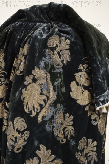 Coronation cloak of King Augustus III, regalia, Augustus III the Saxon King of Poland; Elector of Saxony; 1696–1763. Cloak of dark blue velvet embroidered with silver and gold braided thread and gold lamellar with palmettes. The embroidery is partly directly on the ground, partly appliquéd. The pattern is composed in a repeat format—motifs rhythmically repeated across the entire surface. The repeat consists of larger appliquéd and smaller palmettes embroidered directly onto the cloak. Elaborate larger and smaller palmette compositions with symmetrical arrangements two motif types surround larger and smaller compositions with asymmetrical branches bearing fanciful flowers and strongly curved stems, tilted right and left three branch types in alternating arrangements. The pattern layout is extended in length, with the pattern width equal to the fabric width. The embroidery motifs resemble silk fabric patterns of the period, including lace-like designs. The garment is edged and lined with...