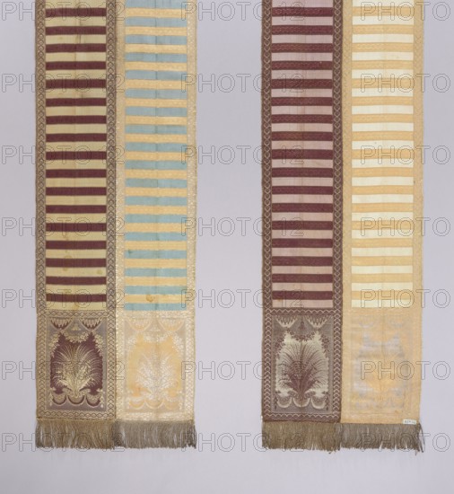 Kontusz belt, 2nd half of the 18th century, Lyon. Materials and features: garlands and festoons ornament; floral ornaments; heads with bouquets of leaves; transverse smooth stripes; solid, four-sided belt construction. Function/style: Polish national costume men's accessory kontusz belt. Dimensions: length 322 cm, width 32.5 cm., A close-up of a pair of long narrow woven textiles hanging vertically against a pale background, each composed of alternating horizontal bands and ornate rectangular panels near the lower ends, with fringed tassels along the bottom edges; colors visible include shades of cream, beige, gold, maroon, brown, light blue, and pale yellow, with maroon stripes set against cream or beige backgrounds on some sections and light blue stripes against pale gold on another, and decorative motifs in gold and brown in the lower panels that feature symmetrical botanical or feather-like patterns, surrounded by patterned borders.