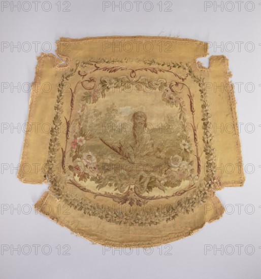 Tapestry hangings; Seat with a depiction of a dog sitting on grass, stage surrounded by a floral and acanthus border. Predominant colors: beige background, green, pink, and brown. Backrest with a depiction of a boy in a theatrical costume against a garden background. Stage framed by a floral and acanthus border in the same tone as the seat. Armrests with a depiction of a garland woven from blooming jasmines. Flowers, floral ornaments, garlands, ribbons; decorative woven upholstery fabric. 18th century, France. Height 73.5 cm, width 78.5 cm., A worn textile panel with a central painted scene framed by ornate floral borders, the fabric predominantly golden yellow with faded greens, soft pinks, muted browns, and cream tones; the central image shows a natural landscape with foliage and what appears to be a standing animal figure amid grasses, surrounded by a garland of roses and leaves in pink, green, and cream, and decorative scrollwork in brown and muted red; the outer field is a solid g...