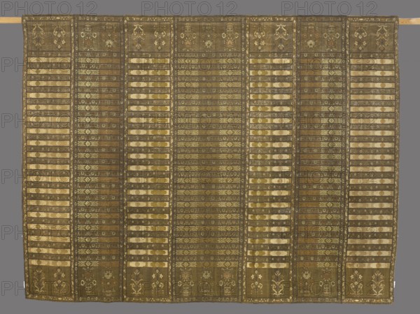 Tapestry, Oskar Potocki's Studio Buczacz; weaving studio; 1879–1913,  studio author, Buczacz tapestries, decorative fabrics, modernism style, Young Poland style, interior furnishings, geometric ornaments, plant ornaments. The tapestry looks as if it were sewn from seven kontusz sashes with short slits. The center is marked by a wide band with heads and three flower bushes in vases; the pattern of the bushes alludes to the sashes of Kraków from the late 18th century. The central wider band is surrounded symmetrically by three narrower bands with two trees on each side: nearest referencing Slutsk sashes from around 1780, then a repeat of the central sash pattern, and at the close another reference to the Slutsk sashes. The tapestry is distinguished by great care in its execution. Motifs from kontusz sashes frequently appear on Buczacz tapestries. ca. 1894, Buczacz place of origin, fabrics, tapestry, height 148 cm, width 199 cm., The image shows a large rectangular textile with vertical p...