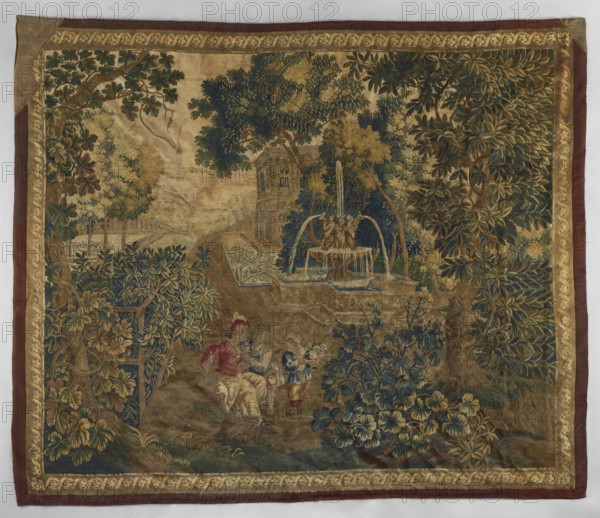 Tapestry - verdure, repossession provenance noted, gardens, landscapes, Fischhorn castle, flowers, floral ornaments, tapestries, decorative fabrics, interior furnishings, fountains, park scenes with architecture, interior decorations, genre scenes against a landscape background. In the background, a garden landscape with a fountain and a fragment of palace architecture. Narrow border imitating a picture frame with a motif of a winding ribbon and rosettes. Colors: green, brown, sand, blue, sky blue, yellow. Density: 5–6 warps/cm, 12 wool–16 silk wefts/cm. 18th century, Europe. Fabrics. Height 291 cm, width 343 cm., The image shows a woven tapestry with an ornate border in gold and brown surrounding a pastoral scene dominated by green, blue, gold, and brown tones; a group of trees with dense foliage in deep green and olive stand at right and left, with lighter green and yellowish leaves interspersed, and a tall tree near the center. A fountain with flowing water rendered in pale blue and...