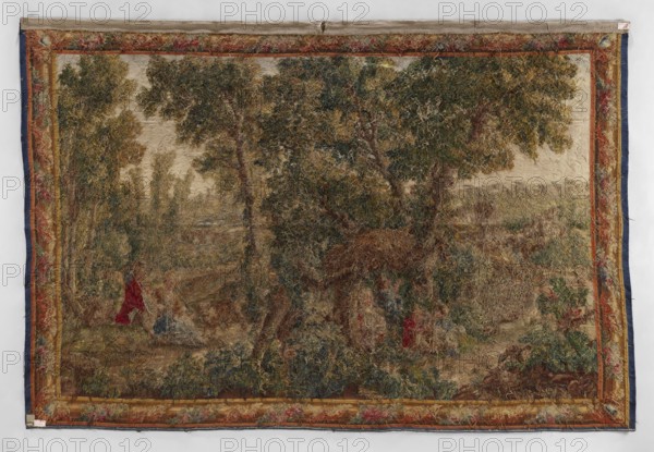 Figural tapestry, Chodecz Kuyavian-Pomeranian Voivodeship; flowers, floral ornaments, dogs, children, women; genre scenes against a landscape background; tapestries, interior furnishings, pastoral scenes, decorative fabrics; In the foreground a group of children playing against a background of tall trees. On the right a girl with a shepherd's staff sits on the grass and a young man next to them a dog. In the background on the right and left there is architecture. Narrow border with a motif of a simple frame entwined with flowers; cartouches in the corners. Colors: green, red, blue, yellow, brown, ochre, and cream. 2nd half 19th century, Germany; fabrics; height 265 cm, width 395 cm, A large rectangular woven tapestry hung flat against a light background, showing a wooded landscape scene with a central group of tall trees with green and olive foliage and brown trunks, surrounded by grassy and shrubby undergrowth in shades of brown, tan, green, and muted blue. Along the edges, a decorati...