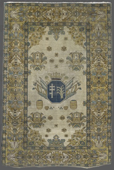 Rug with the Potocki and Mniszech coats of arms. 1st half of the 18th century. Poland Brody ?. Materials: fabrics; height 232 cm, width 158 cm. Features: cartouche under a crown without jewels surrounded by panoplies, next to barrels and spheres; Pilawa Potocki and Mniszech coats of arms and feathers; panoply ornament, maces. Central field decorated with palmettes, small rosettes, and corner sections of large palmettes; four palmettes at top and bottom. Wide three-banded border: two narrow outer bands with geometric motifs and a wide middle band with geometric floral motifs. Colors: off-white background, yellow, green, blue, light blue. Style/ influences: patterns, palmettes and wide border inspired by Turkish carpetmaking; colors and ornamentation refer to contemporary European embroidery. Function: interior furnishing, decorative rug., A rectangular woven rug with an ornate patterned border surrounding a lighter central field, showing a palette of muted gold, beige, blue, gray, and c...