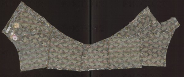 Fabric fragment, droguets finely patterned silk fabric, patterned silk with plant and floral motifs, fragments of clothing, fabric with preserved weft. Colors: pale blue background; wefts from white to blue and dark pink fading to red; green; black weft outline. Droguet: weave where the weft creates colorful decoration, often with warp and weft in different colors; pattern background usually plain weave with motifs formed by unbound wefts liserés. Droguettes often feature small flowers or floral sprigs on textured, often cloud-shaped reserves; used in the 1760s for men's clothing. Dimensions: 4.5 x 5 cm. The preserved fragment is sewn from several parts, which in outline resemble the short spencer coat worn with light dresses at the turn of the 18th and 19th centuries. A garment justokor made of brocade with a similar pattern dates from the late 18th century, France; height 69 cm, width 33 cm., A fabric garment piece laid flat against a dark background, showing a patterned woven textur...