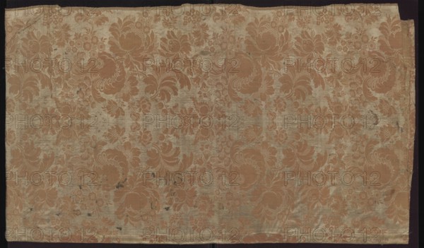Fabric fragment. Fragment sewn from two salmon-white damask-type fabrics promoted stripes, differing slightly in pattern and ply width. 1. Damask effect achieved by different colors of warps and wefts. Pattern in mirror symmetry. Tiny blossoms spill out from large, blooming peony-type flowers. White taffeta background, salmon pattern - gros de Tours. Report: height 29 x width 49.5 cm panel; edge width 0.5 cm. 2. Damask effect achieved by different colours of warps and wefts. Pattern in mirror symmetry. Large fruit and blooming flowers, lace motifs resembling combs of French needlepoint lace. White taffeta background, salmon pattern - gros de Tours. Report: height 38.5 x width 50.5 cm panel; edge width 0.4 cm. Dated 1735–1745, France. Overall fabric fragment: height 98 cm, width 97 cm. Materials: silk, pseudo-damask; patterned floral and plant motifs; stripes; preserved selvedge, ply width, and pattern repeat., A large rectangular piece of fabric with an overall floral damask pattern sh...