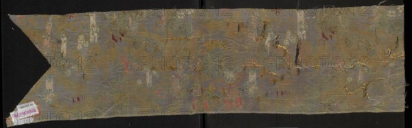 Fabric fragment, origin unknown, early 18th century, France. Fragment cut in the form of a chasuble column with a triangular neckline. Warp-woven liséré satin with a prominent brocaded pattern: blue warp-satin ground with colorful brocade and embroidered threads. Pattern composed of whimsical plant motifs — tiny flowers on slender celadon-green branches and fanciful forms resembling onion-shaped flower buds growing from an ornamentally treated horn-shaped base — and lace-like patterns. Brocade threads: gold, white, pale pink, blue, burgundy; embroidered threads: orange, pink, blue. Right side shows a damask subrapport of liséré satin background and plain weaves decoration; left side has plain weaves. Threads tied in a plain/simple weave. Materials: silk, liséré satin, embellished and brocaded. Report length: 44 cm. Dimensions: height 106 cm, width 23 cm., A long, narrow piece of woven fabric displayed against a dark background, showing a faded, ornate floral and foliate pattern with fl...