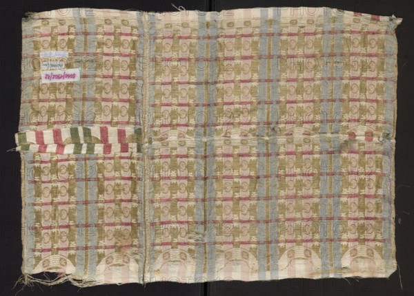 Fragment of fabric, gold-plated, fragments of a larger textile object, fragments of silk fabrics, patterned fabric, striped patterns. Fragment of silk fabric with fine stripes and a stylized plant ornament. The predominant color is dirty-white background with red, green and gold ornament. The closed composition of the pattern indicates it may be a fragment of patterned fabric used for tapestries or as trim/border on larger decorative textiles. Dimensions: width 41 cm; overall height 60.5 cm, width 45 cm. Thread density per 1 cm: 18 white linen, 18 gold on a yellow ground with a loose S braid. Warp density: 46 per 1 cm; edge width 0.4 cm 4 linen warp threads on the edge. Warp satin in the background 1/5. Early 18th century, Europe ., A rectangular piece of woven fabric laid flat on a dark background, showing a repeating checked pattern with ornate motifs; the cloth displays a palette of muted green, pale blue, light pink, cream, and faded red, with vertical blue stripes and narrower red...
