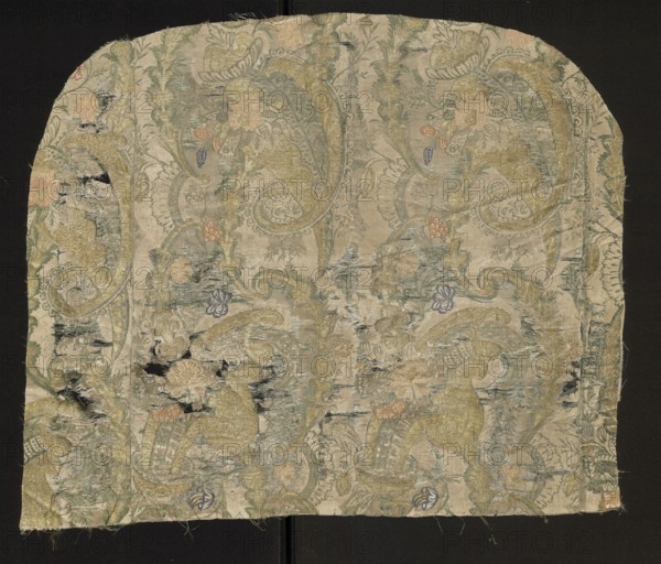 Fabric fragment, fabrics, fragments of a larger textile object, fragments of silk fabrics, patterned fabrics. Flaunted and brocaded silk. Damask subreport - background in a satin weave, pattern in a grosgrain weave, green flaunting thread tied in a twill weave. The white, green, and gold pattern provides a backdrop for colorful floral and fanciful motifs. The asymmetrical fabric report is created by larger forms resembling cornucopias, which intertwine turbinate, lace, and plant motifs. Bizarre decoration. Flaunting thread - green. Padding threads: salmon, pink, blue, gold braided thread. Beginning of the 18th century, France, height 51 cm, width 61 cm; width of the brim: 43 cm, width of the edge: 0.3 cm, width of the report: 23 cm., A rectangular fragment of patterned fabric with rounded top corners laid against a dark background, showing a faded ornate floral and paisley design in pale beige, muted gold, soft green, light blue, and touches of pale pink and lavender; the fabric surfac...