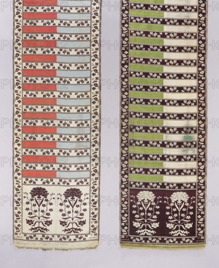Kontusz belt; bipartite heads with a flower bush motif. The stripe is alternately plain and with a floral tendril motif. I - The background of the heads, border, and stripes with tendril is cream-silver, the ornament brown. The smooth stripes are half blue and half red. II - The background of the heads, border, and stripes with tendril is brown, the ornament silver-cream. The smooth stripes are half green and half cream. No fringes. 18th century, Lyon. Clothing accessory for Polish national costume. Length 366 cm, width 32 cm., Two vertical fabric panels hang side by side against a light background. The left panel features alternating horizontal bands of muted red and pale blue separated by cream bands patterned with small dark floral motifs, and a dark floral border along the sides; its lower section shows a cream field with two stylized dark floral tree motifs and a decorative border at the bottom with frayed edges. The right panel displays alternating horizontal bands of light green...