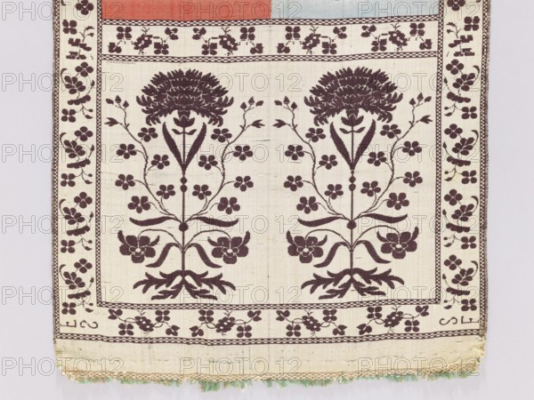 Kontusz belt, 18th century, Lyon. Bipartite heads with a flower bush motif. The stripe alternates plain and with a floral tendril motif. I - The background of the heads, border, and stripes with tendril is cream-silver, the ornament brown. The smooth stripes are half blue and half red. II - The background of the heads, border, and stripes with tendril is brown, the ornament silver-cream. The smooth stripes are half green and half cream. No fringes. Materials/technique: textile clothing accessory for men's national costume. Length 366 cm, width 32 cm. Polish kontusz belt; four-sided belt., A textile with a cream background and a repeating dark brown floral pattern fills the image, showing a symmetrical design of two stylized large flowers with branching stems and clusters of smaller blossoms, bordered by a narrow floral band and a wider outer border with scattered small flowers; the top edge shows a strip of muted coral and pale blue, and the bottom edge has a fringe with pale green and...