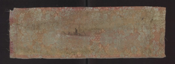 Fabric fragment, fragments of silk patterned fabric, two-color damask, 1st half of the 18th century, France . Salmon-pink plain-weave background with pearly-blue decoration. Two warp colors pink and blue and two weft colors pink and blue. Subornament formed by released warp thread in the background color; in the pattern area the subornament drawing is not connected to the wefts by any weave. Pattern: winding lace ribbon subornament with large and small flowers on winding stems—peonies or roses; stripes and floral motifs. Height 74 cm; edge 0.5 cm; other dimensions unspecified., A rectangular piece of patterned fabric with a faded floral brocade design lies against a dark background; the fabric shows a palette of muted pink, pale blue, beige, and hints of gold, with areas of wear and slight discoloration creating darker beige and brownish smudges; the woven floral motifs include a group of stylized blossoms and leaves repeated across the surface, and the edges of the fabric are frayed w...