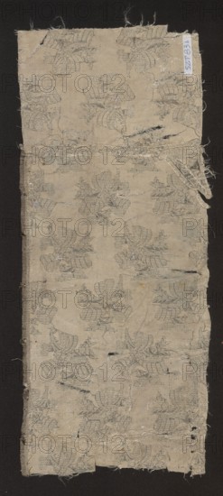 Fabric fragment, 17th century, France. Fragment of silk patterned fabric with preserved design: leafy twigs tied with a ribbon, arranged in rows with shifts and changes of direction. Colors: white and silver background, silver motifs. Pattern size: 12 x 8.7 cm. Overall dimensions: height 46.5 cm, width 39 cm., A rectangular piece of worn fabric with frayed edges placed on a dark background, showing a repeating floral-like woven pattern in muted gray against a beige ground; the fabric has several small tears and holes, loose threads, and patches of wear, with faint darker smudges and slight discoloration in places, and a narrow strip of folded or layered fabric near the top right edge.
