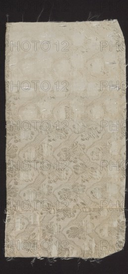 Fragment of fabric, fabrics, fragments of a larger textile object, silk fabric, 18th-century silk fabric, patterned fabric: droguet maurois sur fond taffeta, à petits dessins liserés. A similar fragment constitutes a fragment of a men's habit inventory no. 33068. Report: 5.5 x 7 cm. A drawing of a similar pattern appears in L'Art du fabricant d'étoffes de soie by J. Paulet fig. 195. 1760, Sweden; fabrics, height 38 cm, width 19 cm., A rectangular piece of fabric with frayed edges lies against a dark background; the fabric is a pale off-white or cream color with a subtle woven pattern forming repeating rounded shapes and floral-like motifs in slightly darker and lighter shades of cream; the surface shows a few horizontal slubs and irregularities where threads are worn or pulled, and there are several areas with faint discoloration and small loose fibers along the borders.