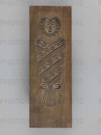 Double-sided gingerbread mould. Side A: image of a bachelor; Side B: baby in swaddling clothes., woodcarver or gingerbread maker. Double-sided rectangular mould. One side shows a man in a long wig and a tricorn hat, dressed in a costume probably dating from the turn of the 17th and 18th centuries: justaucorps with decorative cuffs, culottes, stockings, and high-heeled shoes; at the figure's feet are decorative motifs of flowers and geometric elements and the date 1827. The other side depicts a baby in swaddling clothes richly decorated with geometric and plant ornament. On the edge is an inscription: FW FIEBIGER. a. BAUTZEN. 17 signature of the manufacturer and the beginning of the date., wood gingerbread mould, folk motifs, plant ornaments, floral decorations, historical costumes; Silesia Prussia; 1742–1918 / Bautzen. Date: 1827. Function: form. Dimensions: height 64 cm, width 22.5 cm, depth 4.3 cm., A carved wooden panel shows a stylized wrapped figure with a rounded head and visible...