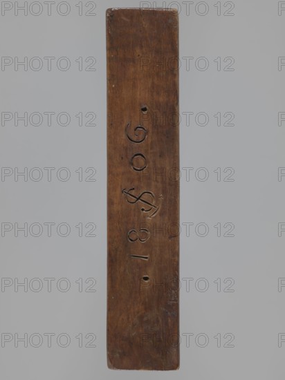 Double-sided gingerbread mould. Side A: bison. Side B: three figures — a bachelor in early 19th-century costume hat, justokor, artificial trousers, high boots, a baby in swaddling clothes decorated with a plant twig, and a fish with an elongated, scaled body. Rectangular wooden mould with the date 1806 engraved on the edge; the date includes the letter S over an anchor manufacturer or gingerbread maker's mark. Gingerbread mould; folk art/folk customs; zoomorphic and figurative motifs; Striding Bull iconography. Dated 1806. Province of Silesia Prussia; 1742–1918. Form. Dimensions: height 19.5 cm, width 10.5 cm, depth 4.3 cm., woodcarver or gingerbread maker., A long vertical wooden plank with a smooth, worn surface in brown tones against a plain light gray background; the plank shows a few carved grooves and shallow round holes along its center, areas of darker and lighter brown from wear, and some subtle scratches and dents.