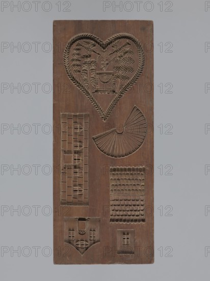 Double-sided gingerbread mould. Obverse: three laurel-wreathed hearts, each containing a scene of a female figure in a garden among trees — first: standing woman in a long dress holding a wreath beside a small garlanded altar; second: seated woman in a long dress among bushes and flowers, leaning on a pedestal with a flying bird to her right; third: seated woman in a dress reading a letter, next to a musical instrument zither?. Reverse: a laurel-wreathed heart containing an altar in a garden with a heart pierced by an arrow, a sun above, and two birds. Decoration includes a fan and various architectural elements. Gingerbread mould, figurative folk motifs, decorative art; rectangular, double-sided form. 19th century, Province of Silesia 1742–1918. Height 31 cm; width 12.7 cm; depth 3 cm., A rectangular carved wooden panel in brown with a carved heart-shaped design near the top containing decorative elements, a fan-shaped carved motif to the right of center, a vertical rectangular grid-l...