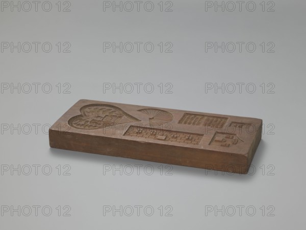 Double-sided gingerbread mould. Obverse: three hearts formed from laurel leaves, each containing allegorical/figurative scenes of female figures in a garden among trees — first: standing woman in a long dress holding a wreath beside a small altar draped with a garland; second: seated woman in a long dress leaning on a pedestal with a flying bird to her right; third: seated woman in a dress reading a letter beside a musical instrument zither?. Reverse: six different representations including a heart formed from laurel leaves containing an altar in a garden with a heart pierced by an arrow, a sun above and two birds; decoration also includes a fan and various architectural elements. Gingerbread mould, gingerbread decorative art, folk motifs, hearts, genre scenes, houses/architectural elements, female figures; rectangular double-sided form. 19th century, Province of Silesia 1742–1918. Height 31 cm, width 12.7 cm, depth 3 cm., A rectangular wooden block with carved recessed shapes rests on...
