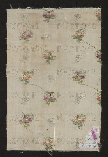 Fabric fragment. Fragment of silver-and-white silk fabric with miniature flower bouquets and floral patterns. Report: length 21.5 cm; overall height 37.5 cm, width 24 cm. 2nd half of the 18th century, France. Materials: silk; patterned fabric., A rectangular piece of light beige fabric with a repeating floral motif scattered across it, showing a few clustered flowers in shades of pink, green, and muted purple with thin green stems, and several faint outline floral sketches in gray; the fabric has a slightly uneven texture and some small stains and worn spots, frayed edges at the top and bottom, and a dark background surrounding the fabric that contrasts with its pale color.
