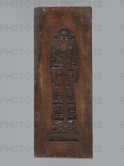 Double-sided gingerbread mould. Obverse: rectangular floral and geometric ornament; a rectangular decorative motif containing a rosette and stylized plants; date engraved on the edge: 1806 with the letter S against an anchor mark of the woodcarver or gingerbread maker. Reverse: figure of the Archangel Michael in a long patterned robe decorated with a plant twig motif, holding scales in his right hand and a sword in his left; at the feet a geometric-plant ornament. Materials/technique: wood, bas-relief. Subject/iconography: Archangel Michael, angels, religious motifs, figurative scene, folk-style decorations, floral ornaments. Maker: woodcarver or gingerbread, Origin/provenance: Silesia Province of Silesia, 1742–1918, unknown specific origin. Date: 1806. Function: gingerbread mould. Dimensions: height 11.6 cm; width 30.5 cm; depth 3 cm., A rectangular wooden panel with a carved vertical figure in low relief occupying the center, the wood showing warm brown and darker brown tones with li...