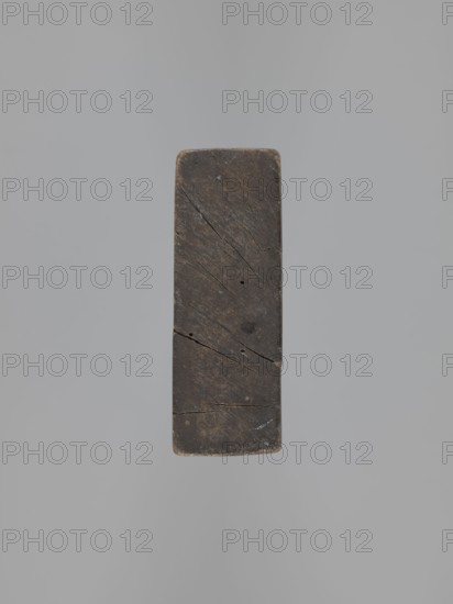 Double-sided gingerbread mould. Obverse: image of Madonna and Child; reverse: small image of Madonna in oval. Double-sided, rectangular form; on one side a figure of Madonna and Child, with a crown on her head, in a long patterned robe decorated with various geometric and plant motifs, the Madonna holds the Child in her left hand and a sword in her right. The other side: a smaller figure of the Madonna in an oval, surrounded by rays, the whole surrounded by a laurel wreath. Materials/function: gingerbread moulds decorative art, folk motifs, religious motifs. Iconography: Madonna and Child, crown, sword, wreath. 19th century, Province of Silesia 1742–1918. Dimensions: height 25.8 cm, width 12 cm, depth 4.5 cm., A rectangular block with rounded corners is centered against a plain light gray background, the block appearing dark brown to nearly black with visible wood grain, scratches, cracks, and small holes across its surface, and slight lighter brown wear along the edges.