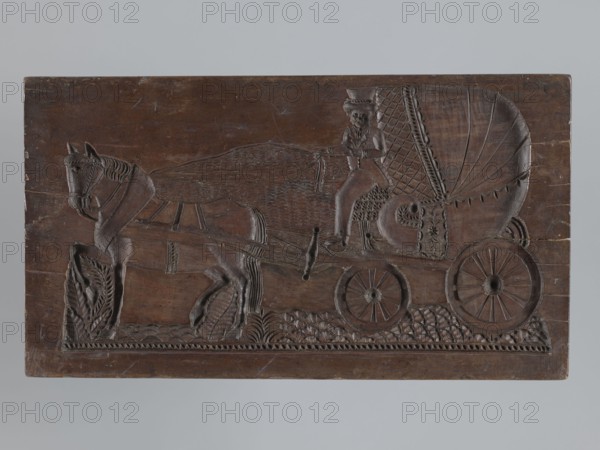 Double-sided gingerbread mould. Obverse: image of a trumpeter on a horse; Reverse: horse-drawn carriage. Double-sided, rectangular mould; on one side, a horseman in a parade uniform from the Napoleonic era playing a trumpet, dressed in a long caftan with epaulettes and braid, trousers with a stripe and long boots; the horse bears a decorative row and a saddle decorated with a floral motif; below is an extensive ornament of flowers, leaves and geometric motifs. On the other side: a two-wheeled covered horse-drawn carriage with a driver on the box wearing a caftan and a high hat; one horse harnessed to the carriage; below is an extensive ornament of geometric and plant motifs. On one edge an engraved inscription: j. Glauer.1828: No 1 signature of the manufacturer or owner of the mould, and the date; on the other edge the inscription: Zum. Andenken. Dated 1828. Materials/function: gingerbread mould, decorative art; motifs include carriages, horse rider iconography, male figures, historica...
