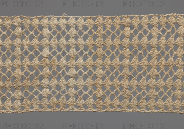Fragment of crocheted lace, section of a belt, cream-colored, with motifs of semicircular shells and small rhombuses in rows., 1st half of the 19th century, probably Germany. Lace, width 7 cm, length 31 cm., A rectangular piece of crocheted lace with a repeating openwork diamond pattern made from twisted yarn, displayed against a neutral gray background; the lace is a natural beige to off-white color with subtle variations creating slightly darker beige areas, and it has a thin crocheted border along the top and bottom edges.