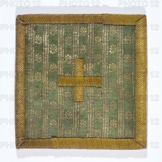 Pall of silk fabric with a fine pattern of stylised floral patterns between gold stripes. Lined with linen. The edge is trimmed with gold galloon. Fabric: background simple weave warp celadon, wefts blue, brocaded with silver metal thread with loose braiding on a white silk base. 18th century. Grodno, Poland. Liturgical vestment. Height 18 cm, width 17 cm. Maker: Pall, unknown., A square textile panel with a green background patterned with vertical stripes and a repeating floral motif in gold tones, bordered by a textured gold trim; a gold cross-shaped applique is centered on the panel.