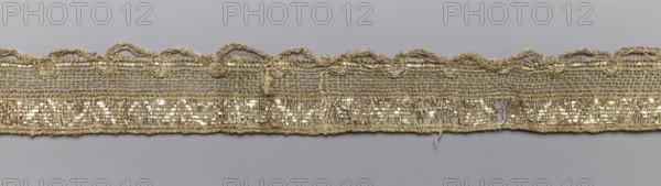 Gallon-lace, galloons haberdashery, origin unknown, haberdashery, 18th/19th century, France, fabric, width 2.7 cm, length 73 cm, A horizontal strip of woven trim with a metallic sheen in gold and pale beige tones stretches across a gray background; the trim features an open mesh upper section with a scalloped, looped edging and a denser lower band that shows a patterned, reflective threading and some loose, frayed threads, with visible texture variations and a few small gaps in the weave.