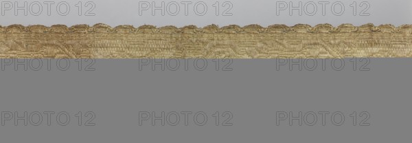 Gallon, haberdashery, origin, 19th century, Lithuania, fabric, haberdashery, width 8.5 cm, length 60 cm, The image shows a horizontal strip of woven fabric with a scalloped top edge against a plain background; the fabric has a textured, slightly shiny surface with visible weave patterns and irregular threads, and the visible colors include shades of gold, beige, light brown, and hints of gray.