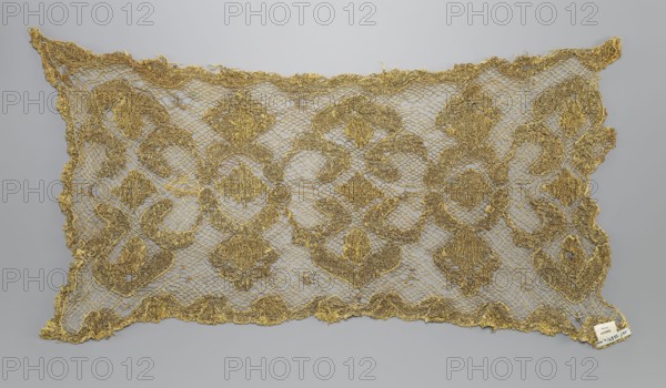 Fragment of lace, lace, 17th/18th century, Belgium, fabric lace, width 34 cm, length 67 cm, A rectangular piece of openwork fabric with a lacy, net-like background and an overlaid ornate pattern, shown against a plain light gray background; the textile is primarily metallic gold in color with variations in tone where the threads form denser motifs, and there are areas of darker gold giving subtle contrast; the lace edges are irregular and scalloped, and the patterned sections form a repeating series of rounded and diamond-like shapes created from thicker, textured gold threads; overall the piece appears thin and delicate with visible holes in the net and slight fraying at the borders.