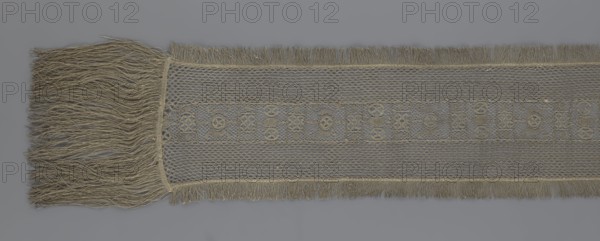 A so-called Saxon lace belt, lace, belts, clothing accessories, men's clothing, clothing, fashion, provenance unknown. The central part is a continuous belt with a geometric ornament; among the motifs is a circle containing an hourglass. The side belts of similar width are permanently connected. The entire belt is trimmed with fringe. 17th/18th century, Poland; lace; height 270 cm, width 25 cm., A long woven textile with fringed ends displayed horizontally, showing a dense group of long loose fringe on the left and shorter fringe along the top and bottom edges; the central band features a delicate mesh-like pattern with a narrower decorative strip of repeating geometric openwork motifs; visible colors include shades of beige, tan, and gray across the fabric and fringe.