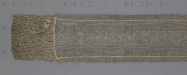 A so-called Saxon lace belt, lace, belts, clothing accessories, men's clothing, clothing, fashion, deposit provenance. The central part is a continuous belt with a geometric ornament; among the motifs is a circle containing an hourglass. The side belts of similar width are permanently connected. The entire belt is trimmed with fringe. 17th/18th century, Poland; lace, clothing accessories, clothing; height 270 cm, width 25 cm, A long, narrow woven textile with a central decorative band and fringed edges, showing shades of beige, tan, gray, and muted gold; one end displays a dense group of long, loose fringe strands, while the main body features an open, lacy mesh pattern with a repeating geometric motif and shorter fringe along the sides, all set against a plain gray background.