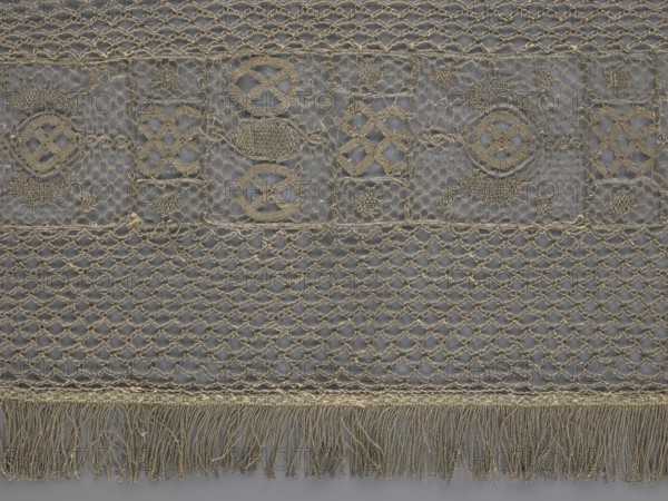 A so-called Saxon lace belt, creator unknown, lace belt for men's clothing, clothing accessory; central continuous belt with a geometric ornament including a circle containing an hourglass; side belts of similar width permanently connected; entire belt trimmed with fringe; 17th–18th century, Poland; lace; height 270 cm, width 25 cm., A close-up view of a textile featuring a repeating openwork pattern in beige and gray tones, with a top band of decorative embroidered motifs set against a gray background, a middle section of a netlike lattice, and a lower fringe of loose threads; the embroidery shows several circular and diamond-shaped stitched elements in beige, the net section displays a repeating diamond mesh also in beige over gray, and the bottom fringe consists of a group of hanging beige threads.