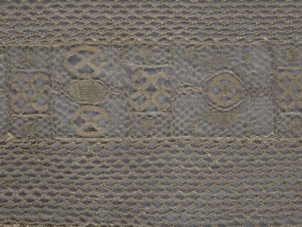 A so-called Saxon lace belt, lace belt as men's clothing accessory; central continuous belt with geometric ornament including a circle containing an hourglass; side belts of similar width permanently connected; entire belt trimmed with fringe. 17th–18th century, Poland. Materials: lace. Dimensions: height 270 cm, width 25 cm., A close-up of a woven textile with a repeating openwork pattern in beige thread against a grey background, showing a band of decorative motifs across the upper third with several circular and diamond-shaped designs and areas of denser woven fill, and a lower area of looser knitted or crocheted mesh with repeating looped rows; visible textures include tightly embroidered sections, looser net-like stitches, and occasional small knots and frayed thread ends.