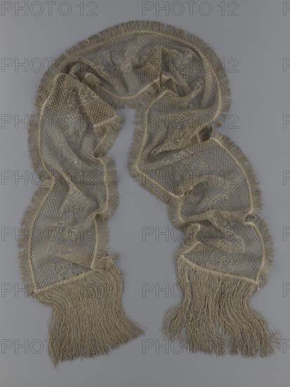 A so-called Saxon lace belt, lace, belts, clothing accessories, men's clothing, clothing, fashion, deposit provenance. The central part is a continuous belt with a geometric ornament; among the motifs there is a circle containing an hourglass. The side belts of similar width are permanently connected. The entire belt is trimmed with fringe. 17th/18th century, Poland; lace, clothing accessories, clothing; height 270 cm, width 25 cm, A long, draped lace-like textile with fringed edges lies against a plain background; the fabric shows an open mesh pattern with denser decorative motifs and scalloped sections along its length, and both ends feature long flowing fringe. The cloth appears in muted beige and tan tones against a cool gray backdrop.