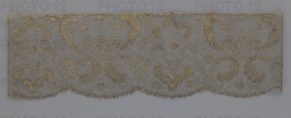 Lace fragment, lace, 18th century, Europe, fabric, width 20 cm, length 120 cm, A rectangular piece of openwork fabric with a scalloped lower edge, showing a repeating decorative pattern of curved motifs and small circular dots set against a fine net background; the fabric appears primarily in shades of gray and beige with highlights of muted gold, and a few frayed threads are visible along the top edge and scalloped border.