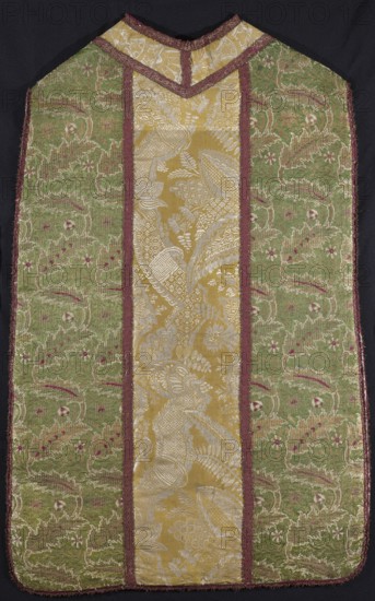 Chasuble, plant ornaments, lace ornaments, patterned fabrics, liturgical fabrics, liturgical vestment. Green chasuble with a yellow column. Sides are of Turkish fabric 17th century with a pattern of winding stems with leaves, strongly tilted alternately to the right and left, and sprigs of small flowers. Background is satin with a warp cover — greens, patterns highlighted with gold, cream, and red wefts. Gold threads with braiding. Column of yellow and white French fabric 17th century. Column of yellow and white stripe. Lace pattern highlighted with white weft. Side fabric — repeat length 16.5 cm; column fabric — repeat length 61–61.5 cm. Background with a rep texture tied in a plain weave, pattern highlighted with white weft. Divisions and sides trimmed with red and gold galloon. Edges with narrow, frayed galloon. 17th/18th century, France column, Turkey sides. Liturgical vestment. Dimensions: length 105 cm, width 63 cm back., A single ornate textile garment with a central vertical pa...