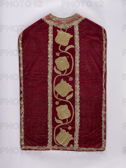 Chasuble, Liturgical vestment, end of 17th century embroidery. Central column embroidered with gold on a backing; sides of pressed velvet. Center columns of smooth velvet with sewn-on gold embroidery on a backing featuring a thick floral tendril. Trimmed with narrow silver bobbin lace. Cotton lining; neckline of red silk. Embroidery: metal thread; embroidery laid and flat on metal-thread backings gold-colored plate woven on linen yarn? held with linen yarn. Leaves, stems, and buds embroidered directly on velvet; flower chalice embroidered on a separate linen canvas backing and appliquéd. Materials include Italian fabric. Function: liturgical vestment. Dimensions: length 107 cm, width 65.5 cm back., A rectangular textile with a rounded top displayed against a light background, predominantly deep red with a vertical central panel in a similar red tone bordered by a decorative trim in a metallic gold color; the central panel features a repeating floral vine motif in metallic gold with sty...