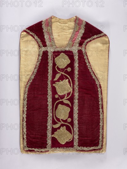 Chasuble, Liturgical vestment, 17th century end of 17th century - embroidery. Central column embroidered with gold on a backing; sides made of pressed velvet. In the columns: smooth velvet with sewn-on gold embroidery on a backing with a thick floral tendril. Trimmed with narrow silver bobbin lace. Cotton lining. Neckline of red silk fabric. Embroidery: metal thread; embroidery laid and flat on metal thread backings gold-colored plate woven on linen yarn? held with linen yarn. Leaves, stems, and buds embroidered directly on velvet; flower chalice embroidered on a separate linen canvas backing and appliquéd. Materials: fabric from Italy; origin: Poland. Function: liturgical vestment. Dimensions: length 107 cm, width 65.5 cm back., A garment laid flat on a pale background with a rich red velvet central panel and side panels, framed by metallic gold trim and lace; the inner fabric is a light beige or cream color, visible on the shoulders and sides. The red velvet areas have a ribbed textu...