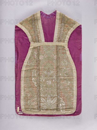Chasuble, Liturgical vestment made of two types of lace fabrics: the front and sides of the back are silver-colored fabric embellished with a pattern of large plant motifs. The column on the back is satin, straw-colored fabric embellished with colored silk motifs, large fantastic flowers and leaves growing from a small basket. Columns trimmed with silver lace; edges trimmed with wide silver lace. Red silk lining. Height 66 cm; column height 30 cm. Date: 1st quarter of the 18th century front and sides of the back: 1720–25; column on the back: ca. 1715. Place of origin: France. Length 106.5 cm; back width 66 cm., A garment laid flat against a pale background, predominantly showing a deep magenta fabric with an inset central panel of ornate brocade in soft gold, pale green, and muted peach tones; the magenta forms the sleeves and outer border while the brocade panel features an intricate symmetrical floral and foliate pattern with raised metallic threads and a sheen; the brocade is edged ...