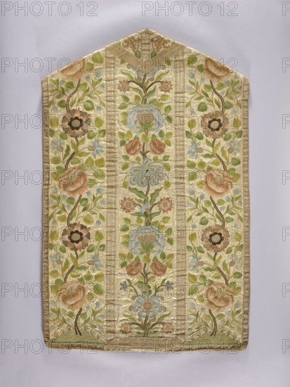 Chasuble, Mid-18th century. Cotton lining. 18th century, Poland. Liturgical vestment. Length 110 cm, width 70 cm back. Description: In the column on the back, a floral tendril running straight—flower bouquets growing one from another, with fantastic flowers resembling peonies, roses, daffodils, carnations, and bellflowers. The tendrils grow from a green mound with low grass. On the sides of the back, similar flowers appear on a distinct tendril growing from the mound; the flowers are more fantastical. On the front column, three flower bouquets grow from the previous ones. The columns are trimmed with wide gold braid and narrower braid at the edges. Plant ornament, church parament, sacred art., A textile panel with a pointed top displayed against a pale background, featuring an embroidered floral design in soft colors; the main background of the fabric is a creamy beige, with embroidery in shades of green, light blue, pale pink, tan, brown, and muted gold. The pattern is arranged in ver...