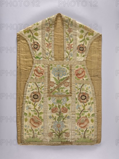 Chasuble, Mid-18th century, Poland. Liturgical vestment. Cotton lining. Length 110 cm, width 70 cm back. Decoration: floral plant ornaments—roses, carnations, daffodils, peonies, bellflowers—arranged as floral tendrils and bouquets growing from green mounds with low grass on the back column and sides; similar but more fantastical tendrils and flowers on the front. Columns trimmed with wide gold braid and narrower edge braid. Sacred art; church parament., A decorative garment front with a sleeveless, V-shaped top and a rectangular lower section, made of a pale gold-beige fabric with embroidered panels; the embroidery forms vertical and horizontal bands creating a grid of panels filled with floral motifs, including stylized blossoms, buds, and stems. The visible colors include shades of pale gold, beige, cream, soft green, light blue, muted pink, coral, brown, and touches of darker green; the background fabric is a warm beige-gold. The embroidered flowers are arranged symmetrically, with...