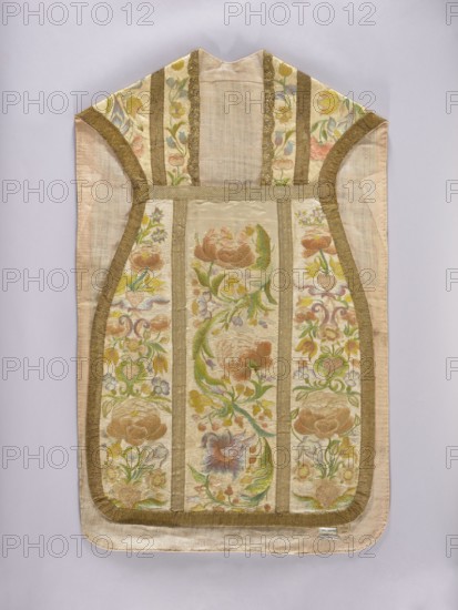 Chasuble, Liturgical vestment made of white silk satin, embroidered with colorful silk threads. The columns feature a wide, richly flowered tendril with large flowers in the bends and small ones along the tendrils. The sides are decorated with floral sprigs placed one above the other and growing from heart-shaped vases. Predominant colors: pink in several shades, green, and blue. Edges trimmed with wide gold braid; columns trimmed with narrower braid. Cotton lining, light pink. Dated 1st half of the 19th century 18th century, Poland noted. Length 107 cm, width 66 cm back. Subjects/ornament: flowers, plant tendrils, plant ornaments; church paraments; sacred art; churches and chapels furnishings., A sleeveless textile garment displayed flat with a rounded bottom and a pointed top, featuring a central panel and side panels separated by vertical bands of trim; the fabric shows embroidered floral motifs with large stylized flowers and curling leafy vines. The visible colors include cream an...
