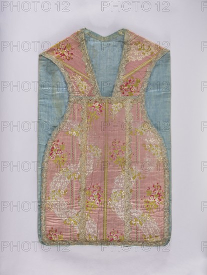 Chasuble, origin unknown, lace ornaments, floral ornaments and bouquets, flowers and leaves, plant ornaments; liturgical vestment for church use, sacred art; predominant colors: light plum background with white, green, and cherry-red ornaments; trimmed with silver lace; blue cotton lining; 2nd half of the 18th century, France; length 104 cm, width 62 cm back., A sleeveless garment laid flat with a V-shaped neckline, featuring a central panel of pink fabric with vertical ribbing and floral patterns in shades of green and pink, bordered by metallic lace trim; side and upper shoulder panels of pale blue fabric; overall trim and decorative edging in a metallic gold or silver tone; background in light gray; visible colors include pink, pale blue, green, gold, silver, and white.