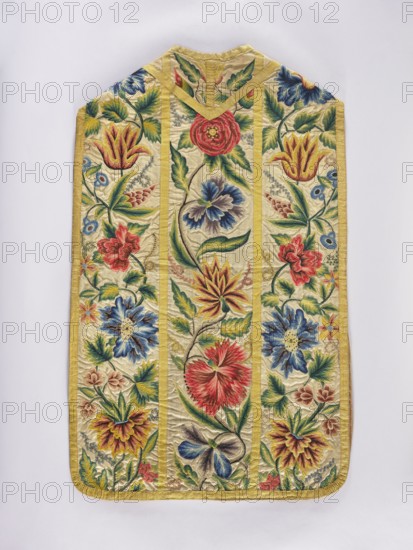 Chasuble, Chasuble made of woolen canvas embroidered with patterns of large, fantastic, diverse flowers on a common stem; embroidery colors green, blue, yellow, brown, red. Trimmed with yellow silk braid. Cotton lining. 18th century, Silesia. Liturgical vestment. Length 106 cm, width 65.5 cm., A decorative textile panel with a pale yellow background and a yellow border features a vertical triptych of panels filled with embroidered floral motifs; a few large stylized flowers in red, blue, and yellow appear alongside several smaller blossoms and leafy stems in shades of green, with accents of pink, brown, and purple. The embroidery shows layered petals and textured stitching creating depth, with curving vines and leaves running through each panel. The overall shape is tapered at the top with a small notch and rounded bottom corners, and the colors include pale yellow, bright yellow, red, various blues, green, pink, brown, and purple.