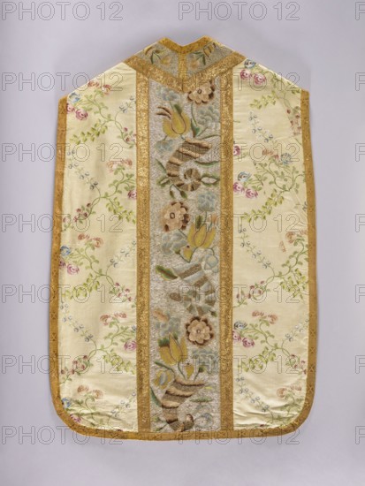 Chasuble made of cream-colored silk brocaded with a pattern of leafy, twisting twigs bearing small fruits and rose blossoms. Brocade threads in pink, blue, and green. The columns at the front and back are embroidered with cornucopia motifs from which bouquets of flowers grow, including tulips and roses; columns have a gold background with ornament in pink, yellow, and blue. Gray linen lining. Mid-18th century, Poland. Liturgical vestment; length 112 cm, width 72 cm back., The image shows a long decorative textile with a pale cream background and a central vertical panel framed by golden trim; the panel contains a patterned design with floral motifs and curved striped shapes in muted browns, greens, and blues, and there are additional scattered floral sprigs across the cream sections in pink, green, blue, and pale yellow. The edges are finished with a golden border, and the top has a small V-shaped notch also trimmed in gold. The overall colors visible include cream, gold, brown, green,...