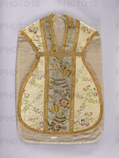 Chasuble, Chasuble made of cream-colored silk brocaded with a pattern of leafy, twisting twigs bearing small fruits and rose blossoms; brocade threads in pink, blue, and green. Front and back columns embroidered with cornucopia motifs producing bouquets of flowers, including tulips and roses; gold background of the columns, ornament in pink, yellow, and blue. Gray linen lining. Mid-18th century, Poland. Liturgical vestment. Length 112 cm, width 72 cm back., A textile garment with a symmetrical, sleeveless shape is shown flat against a pale background; the main fabric is a light beige or tan with panels of cream or ivory silk featuring embroidered floral motifs, and a central vertical panel with multicolored woven flowers and leaves. Several narrow bands of gold trim run vertically and outline the panels, creating a framed pattern, while the embroidered flowers include shades of pink, green, blue, brown, and yellow. The overall palette includes beige, cream, gold, pink, green, blue, yel...